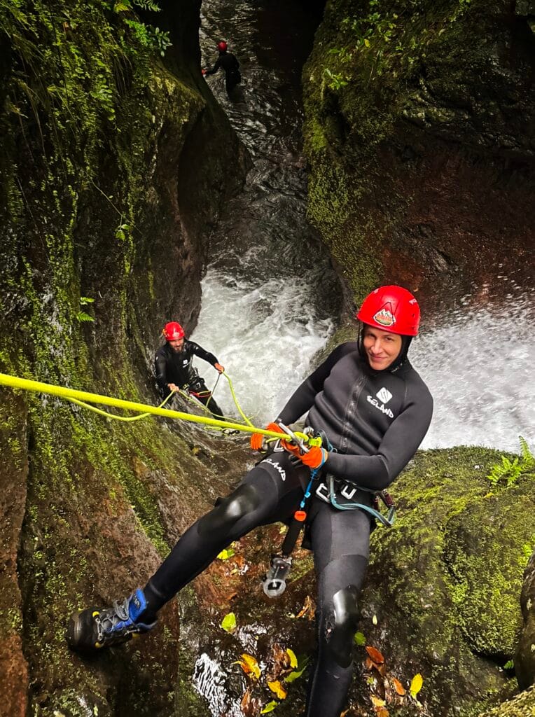 Scoot hangs off a waterfall as he abseils and repels during canyoning vs coasteering in Madeira