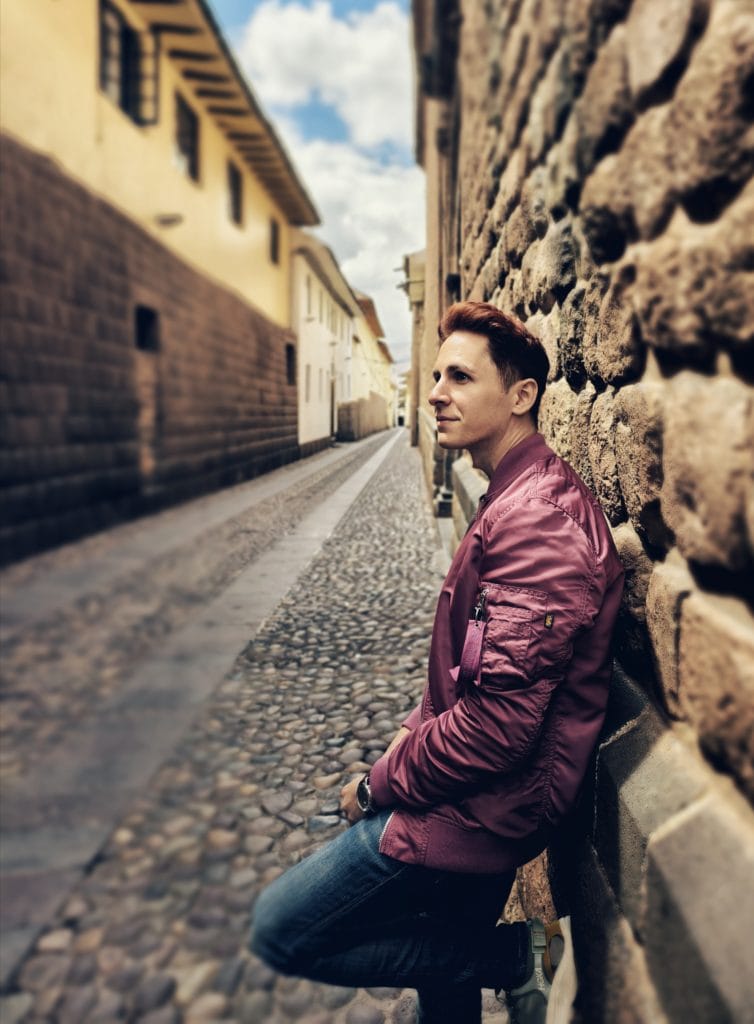 Scoot standing beside an ancient Inca stone wall in the historic center of Cusco