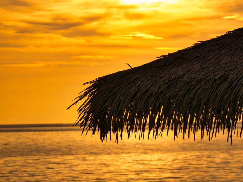 Golden hour sunset over a luxury overwater bungalow in the Maldives.