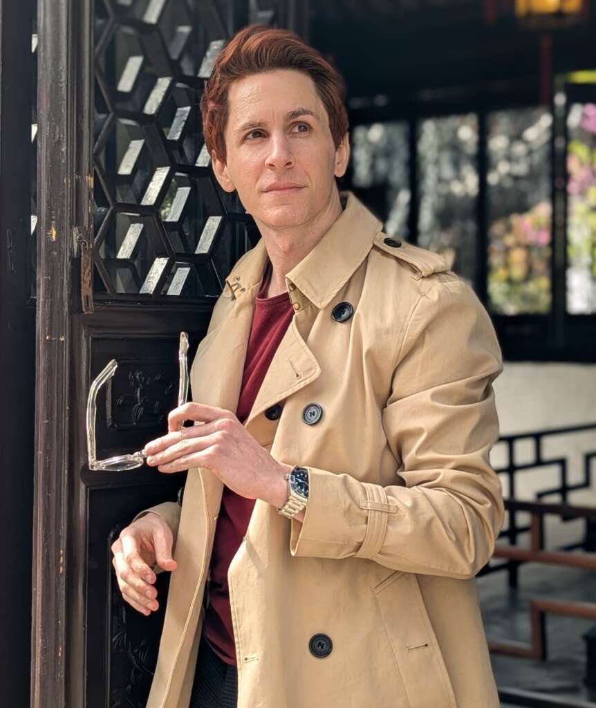 Man with red hair and trendy trench coat travels
