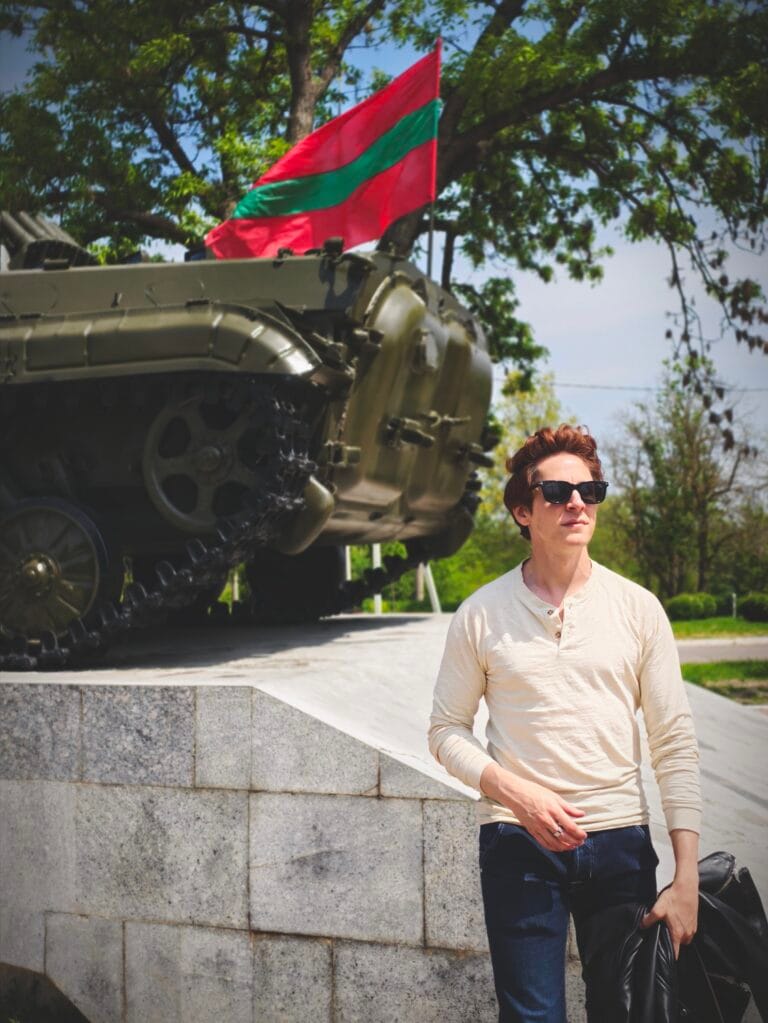 Scoot posing in front of a tank with the Pridnestrovie flag