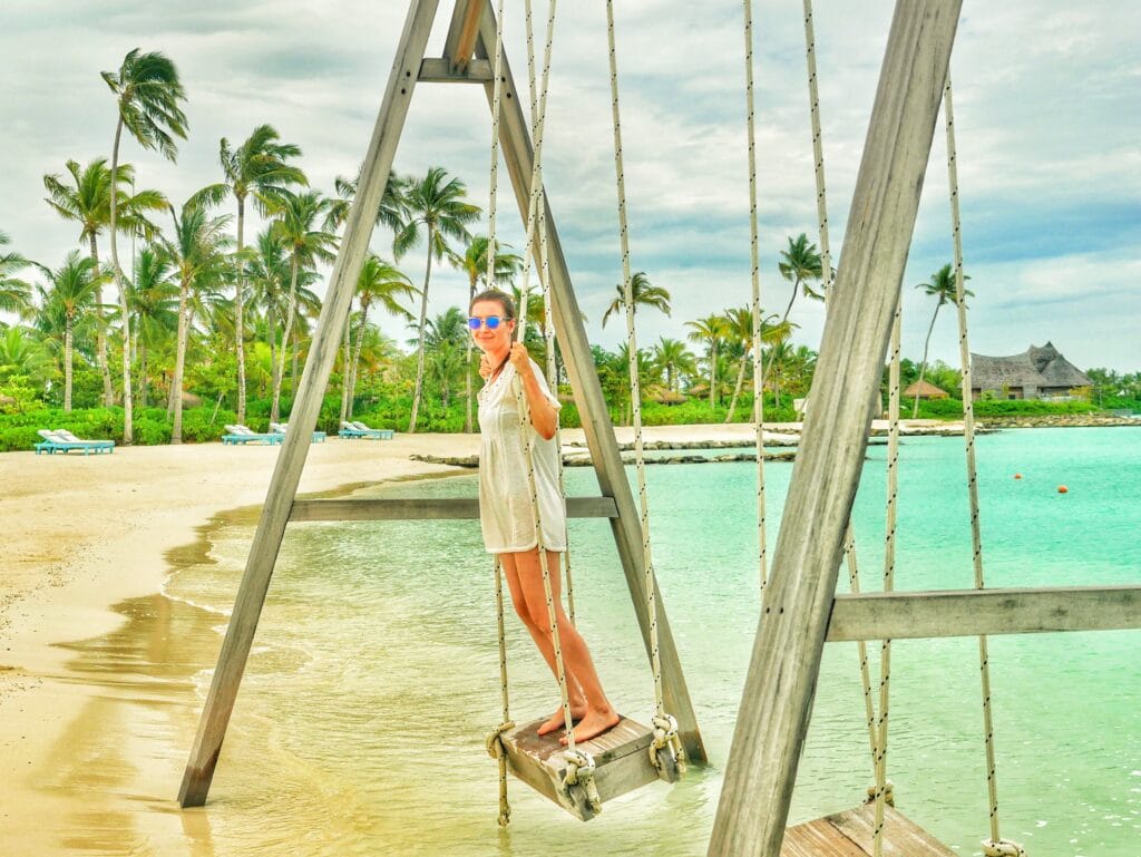 Z standing on a beach swing in the Maldives at dusk.
